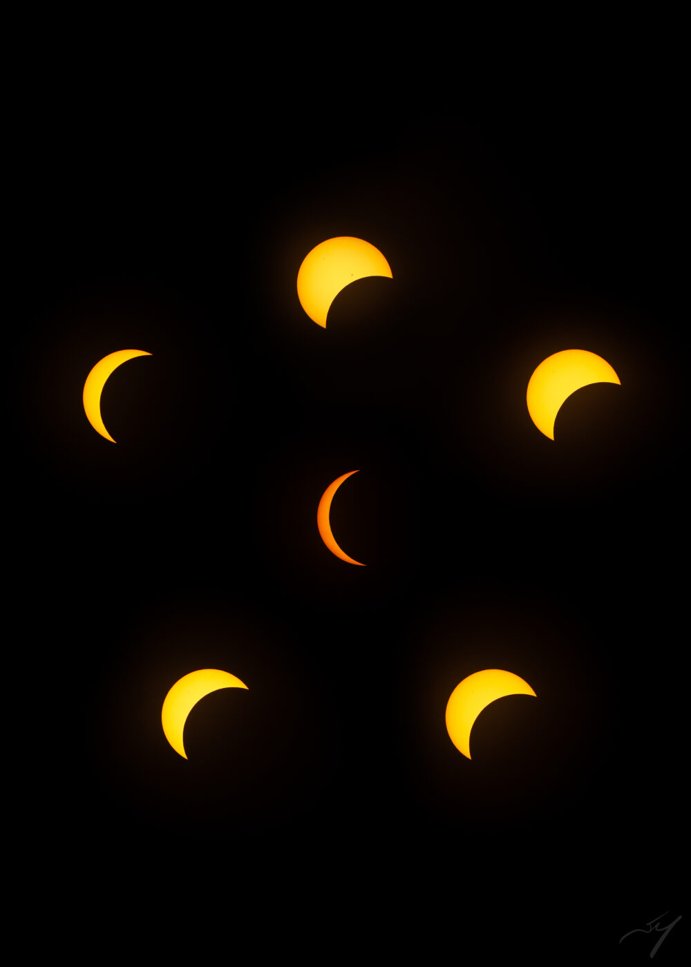 Six images of a partially-obscured sun during a solar eclipse, arranged in a pentagonal pattern with maximally-eclipsed sun crescent in the centre.